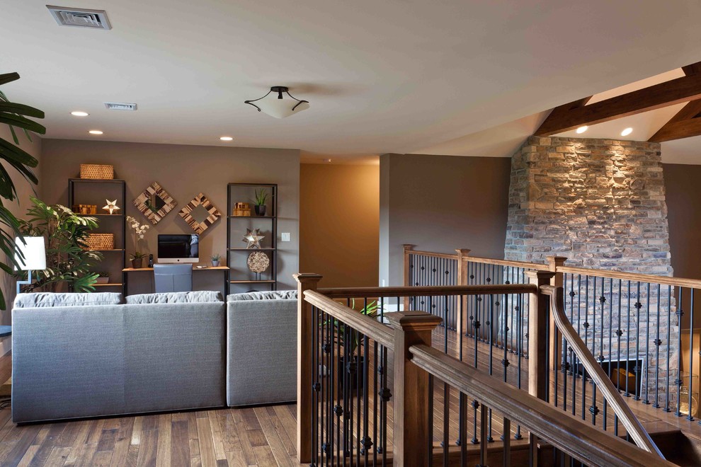 На фото: большая изолированная гостиная комната в стиле кантри с коричневыми стенами, ковровым покрытием, стандартным камином, фасадом камина из камня, телевизором на стене и бежевым полом