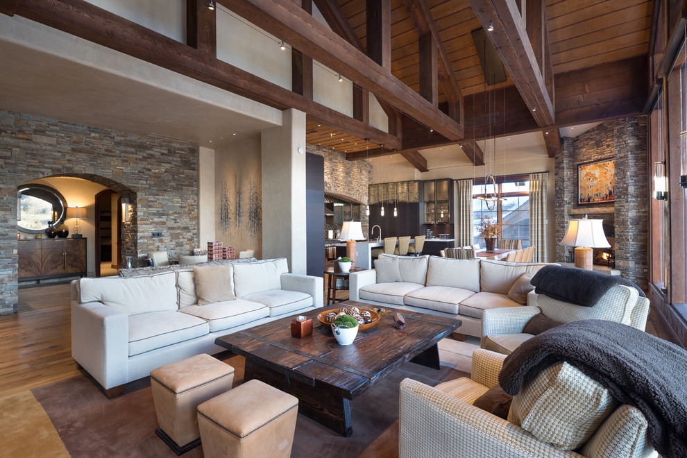Design ideas for a large rustic open plan living room in Other with grey walls, light hardwood flooring, a standard fireplace, a stone fireplace surround and beige floors.