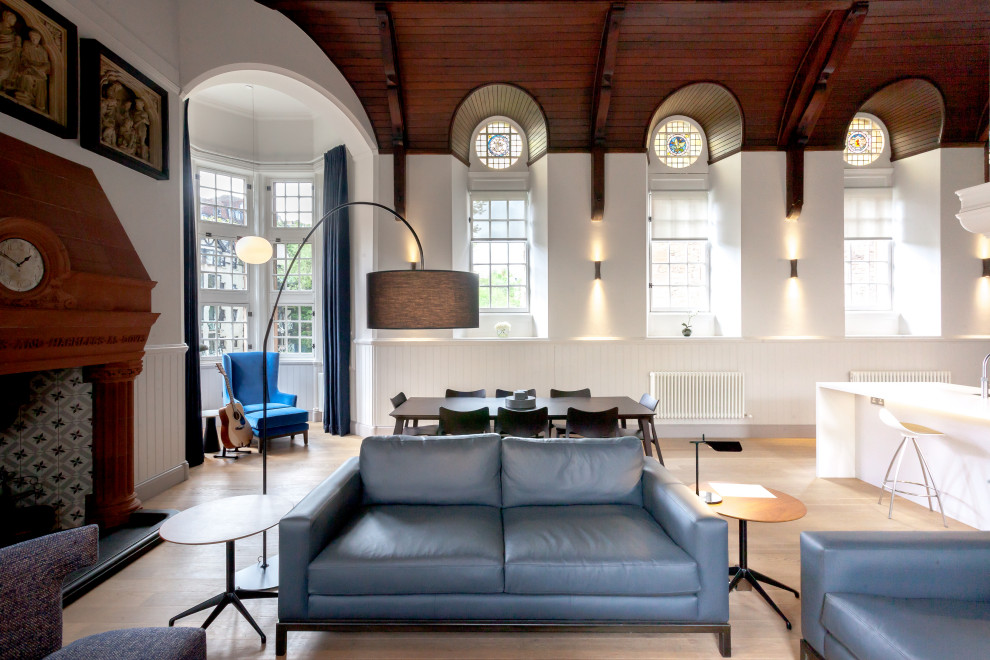 Inspiration pour un salon design ouvert avec un mur blanc, parquet clair, une cheminée standard, un sol beige, un plafond voûté et boiseries.
