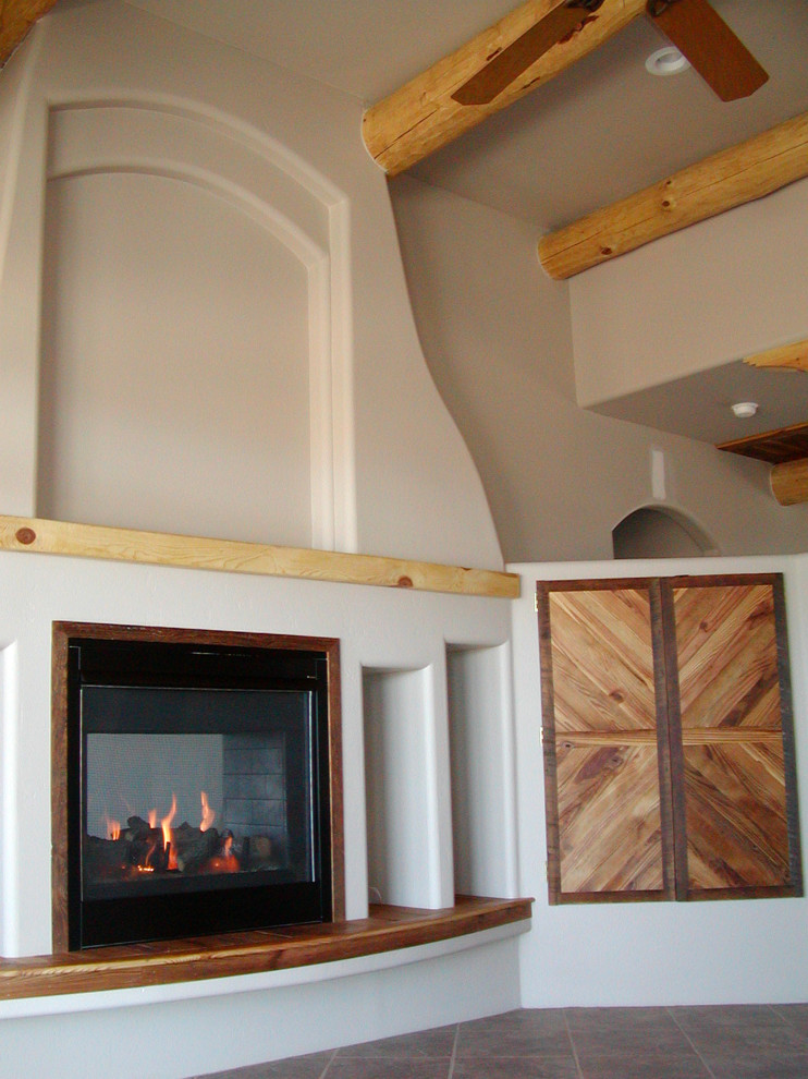 Modelo de salón abierto de estilo americano grande con paredes blancas, suelo de baldosas de cerámica, chimenea de doble cara y marco de chimenea de madera