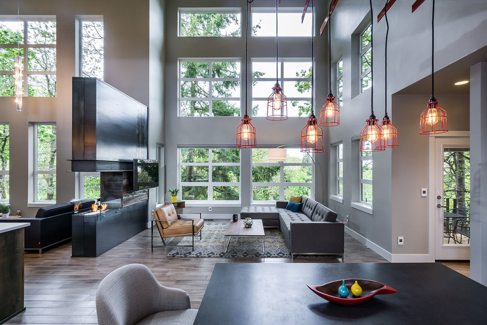 Foto di un soggiorno minimalista di medie dimensioni e aperto con pareti grigie, pavimento in legno massello medio, camino bifacciale e TV a parete