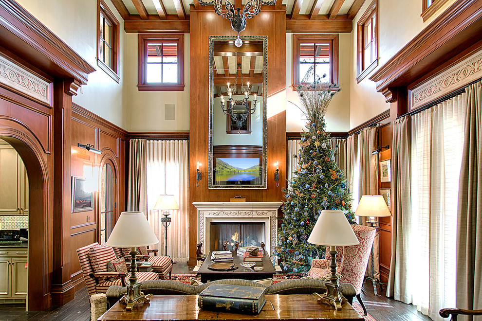 Пример оригинального дизайна: большая открытая гостиная комната в классическом стиле с бежевыми стенами, темным паркетным полом, стандартным камином, фасадом камина из дерева, скрытым телевизором и коричневым полом