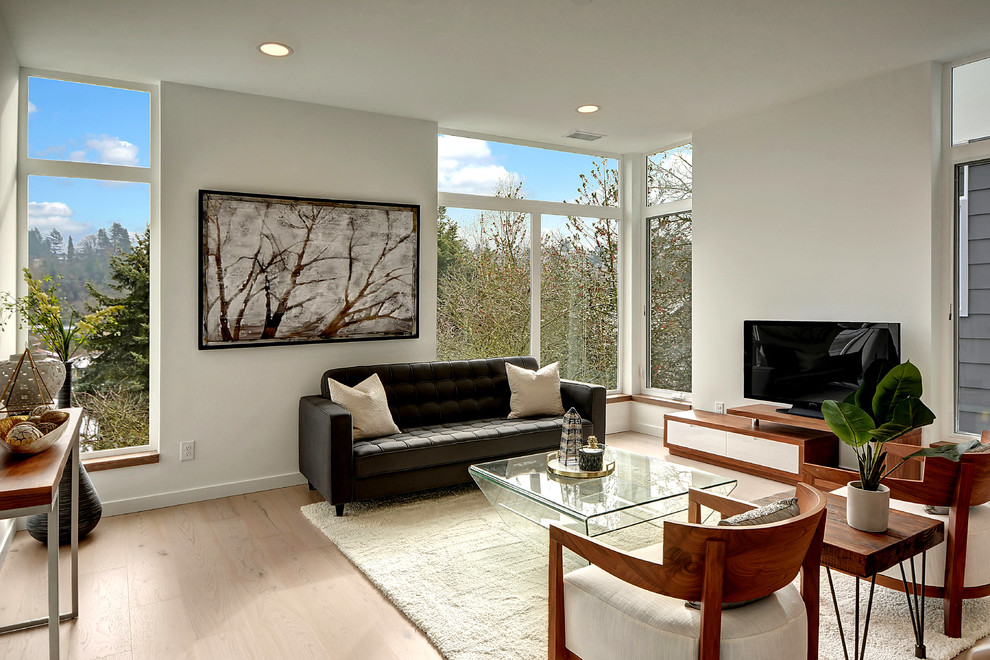 Offenes Modernes Wohnzimmer mit weißer Wandfarbe, hellem Holzboden, freistehendem TV und beigem Boden in Seattle
