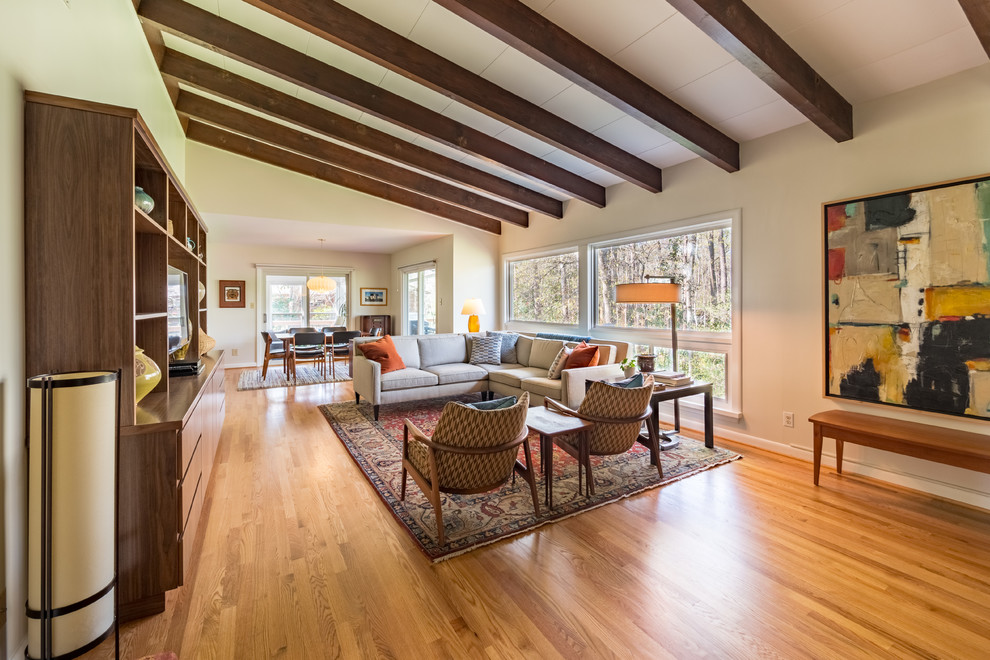 Diseño de salón abierto retro con paredes beige, suelo de madera en tonos medios y suelo marrón