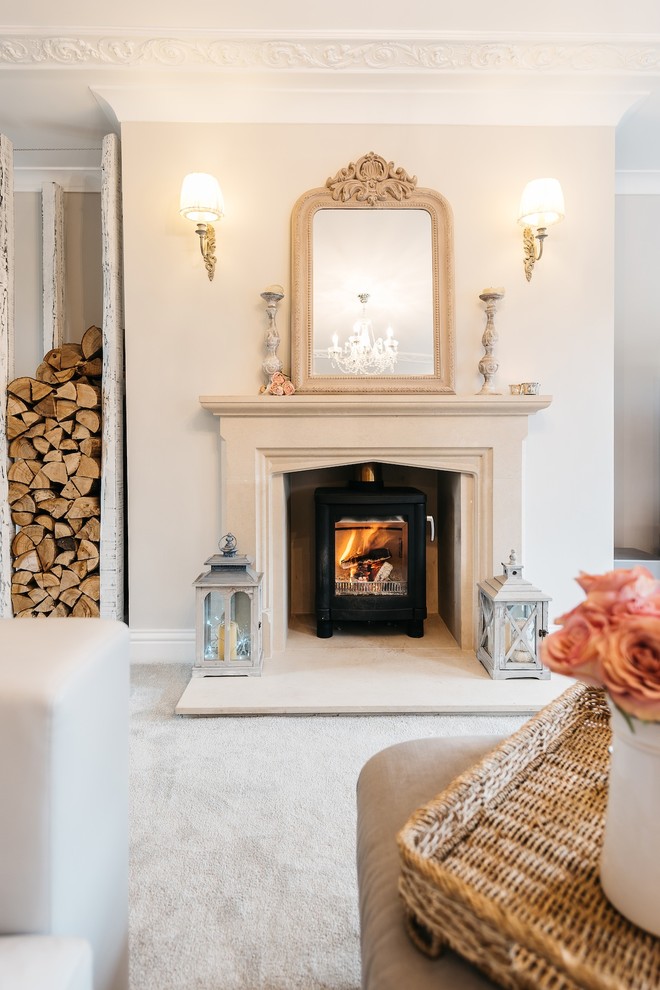 Exemple d'un salon romantique avec moquette, un poêle à bois, un manteau de cheminée en pierre et un mur gris.