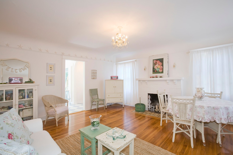 Cette image montre un salon style shabby chic avec un mur blanc, un sol en bois brun et une cheminée standard.