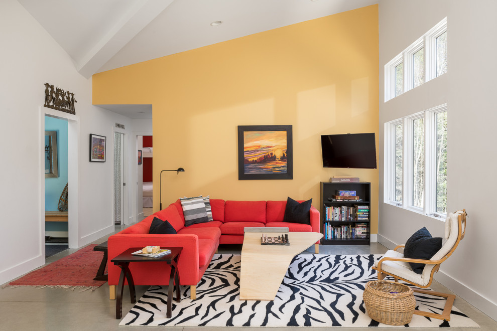 Пример оригинального дизайна: маленькая изолированная гостиная комната в стиле модернизм с желтыми стенами, бетонным полом, телевизором на стене, серым полом и сводчатым потолком для на участке и в саду