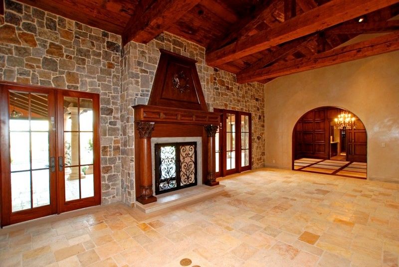 Exemple d'un grand salon montagne fermé avec une salle de réception, un mur beige, un sol en calcaire, une cheminée standard et un manteau de cheminée en bois.
