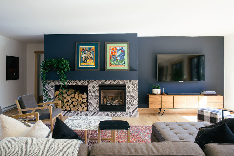 Offenes Retro Wohnzimmer mit blauer Wandfarbe, hellem Holzboden, Kamin, TV-Wand und beigem Boden in Sonstige
