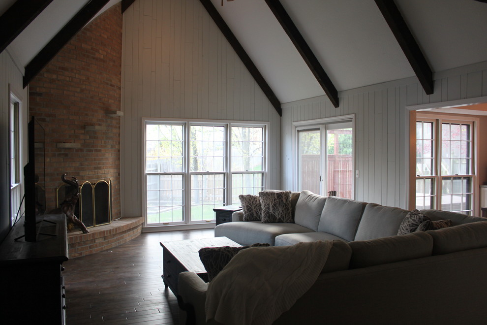 Exempel på ett mellanstort klassiskt separat vardagsrum, med vita väggar, mörkt trägolv, en öppen hörnspis, en spiselkrans i tegelsten och en fristående TV
