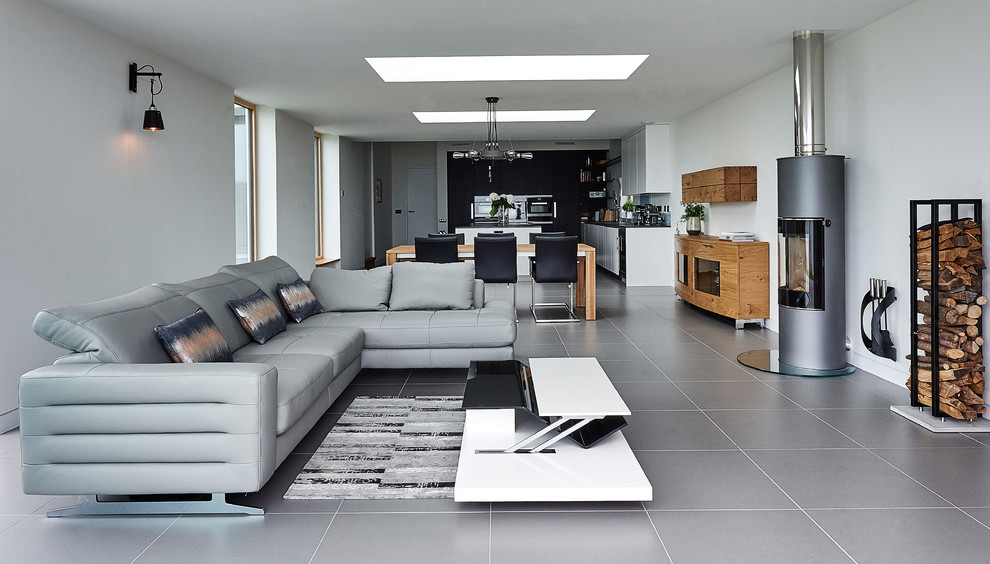 Cette photo montre un salon tendance ouvert et de taille moyenne avec un mur blanc, un poêle à bois, un manteau de cheminée en métal, aucun téléviseur et un sol gris.