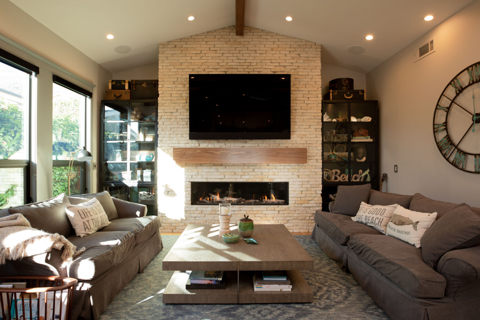 Beach style open plan living room in San Luis Obispo with beige walls, medium hardwood flooring, a ribbon fireplace, a stacked stone fireplace surround, a wall mounted tv and brown floors.