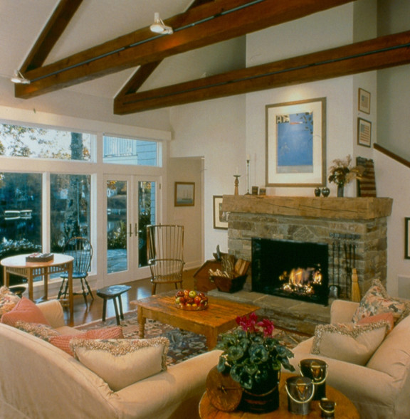 Exemple d'un grand salon romantique avec un mur blanc, un sol en bois brun, une cheminée standard, un manteau de cheminée en pierre et aucun téléviseur.