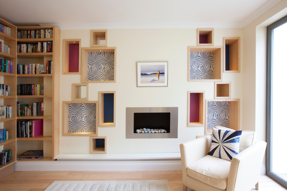 Modelo de biblioteca en casa cerrada minimalista de tamaño medio sin televisor con paredes beige, suelo de madera en tonos medios y todas las chimeneas