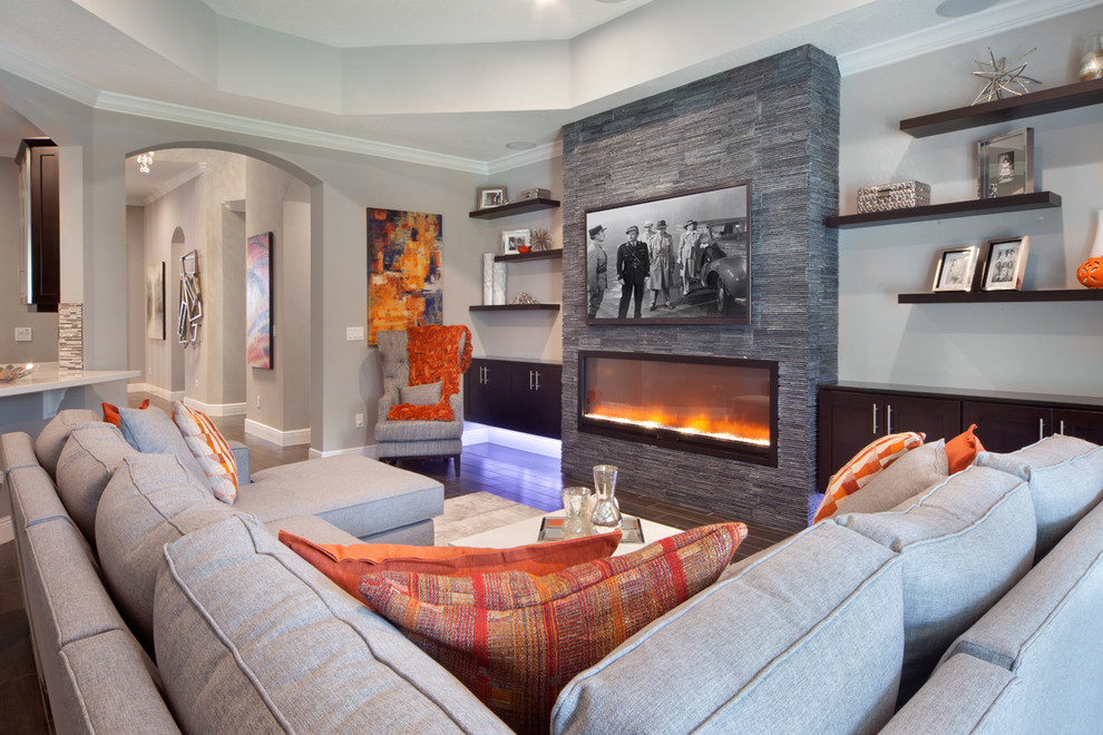 Свежая идея для дизайна: открытая гостиная комната среднего размера в стиле неоклассика (современная классика) с серыми стенами, горизонтальным камином, фасадом камина из камня и телевизором на стене - отличное фото интерьера