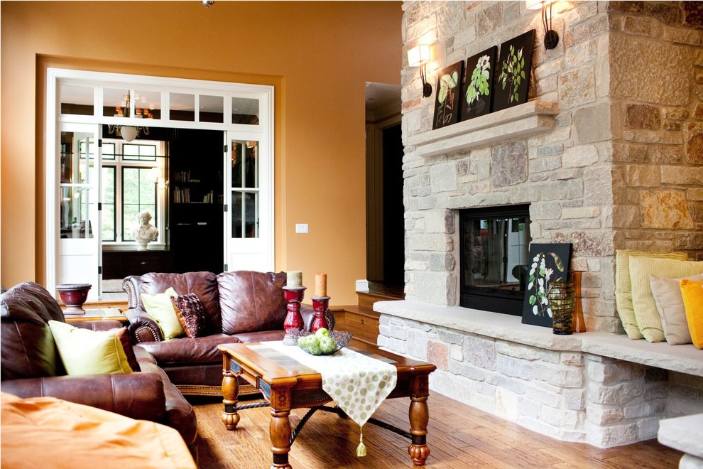 Diseño de salón clásico sin televisor con paredes amarillas, suelo de madera en tonos medios, todas las chimeneas, marco de chimenea de piedra y suelo marrón