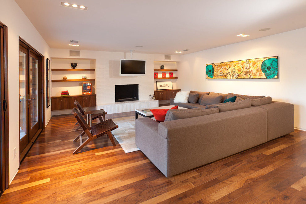 Modelo de salón abierto minimalista de tamaño medio con paredes blancas, suelo de madera oscura, chimenea lineal, marco de chimenea de piedra y televisor independiente