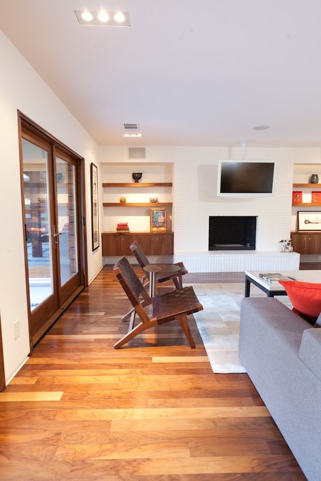 Photo of a medium sized modern open plan living room in Sacramento with dark hardwood flooring, white walls, a brick fireplace surround and a freestanding tv.