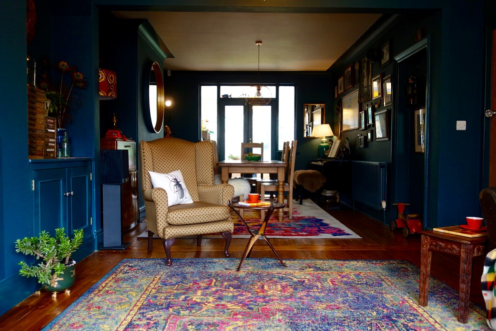 Aménagement d'un grand salon éclectique ouvert avec un sol en bois brun, aucune cheminée, un manteau de cheminée en plâtre, un téléviseur indépendant et un mur bleu.