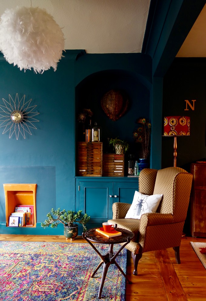Réalisation d'un grand salon bohème ouvert avec un sol en bois brun, aucune cheminée, un manteau de cheminée en plâtre, un téléviseur indépendant et un mur bleu.