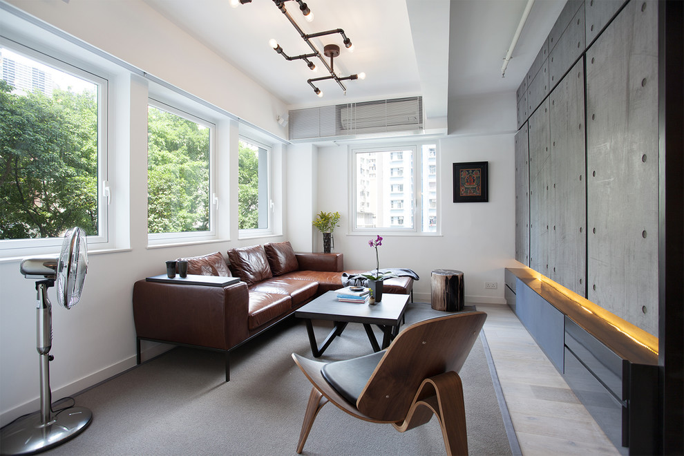 Ejemplo de salón urbano sin chimenea con paredes blancas, suelo de madera clara y televisor retractable