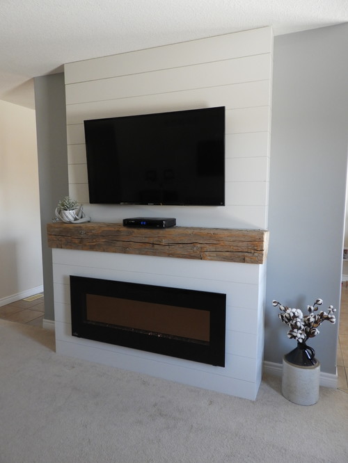 Custom shiplap fireplace design with electric fireplace insert, elm barn beam and wall mounted TV.
Inspiration for a mid-sized country enclosed carpeted and beige floor living room remodel in Toronto with gray walls, a hanging fireplace, a wood fireplace surround and a wall-mounted tv 