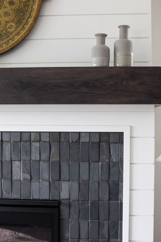 グランドラピッズにあるコンテンポラリースタイルのおしゃれなリビング (標準型暖炉、タイルの暖炉まわり、茶色い床、塗装板張りの壁) の写真