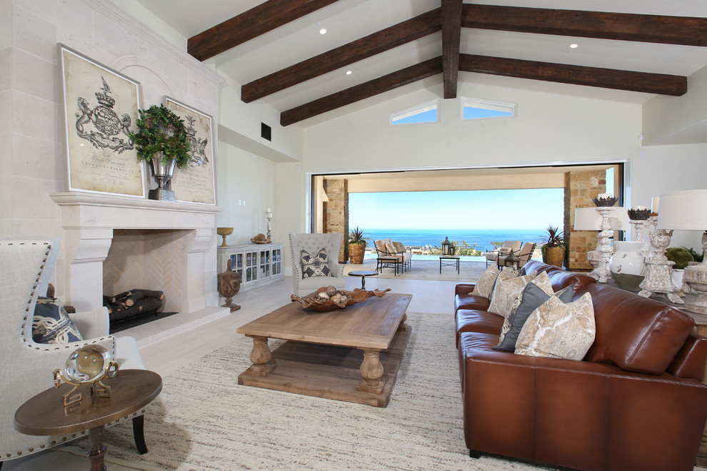This is an example of an expansive nautical open plan living room in Orange County with beige walls, travertine flooring, a standard fireplace and a stone fireplace surround.