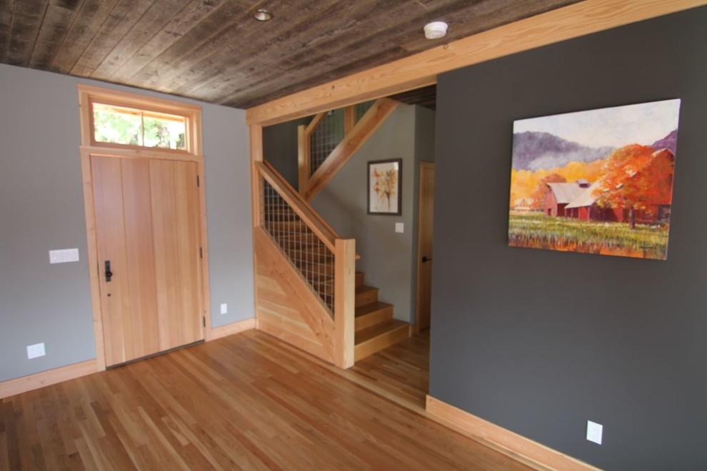 Cette image montre un salon minimaliste de taille moyenne et ouvert avec une salle de réception, un mur gris, parquet clair, une cheminée standard et un manteau de cheminée en béton.