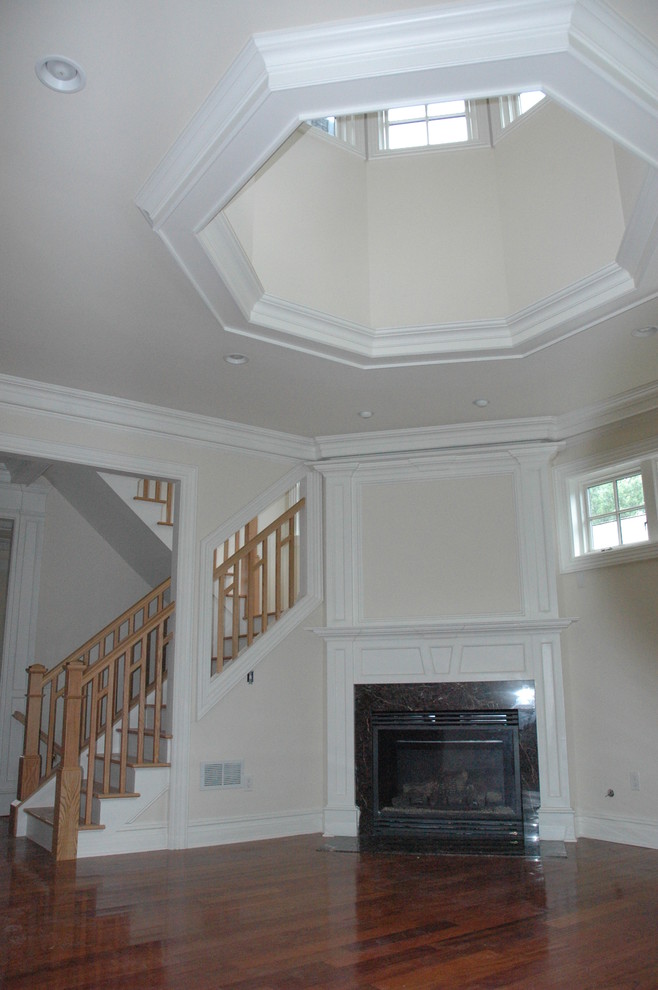 Aménagement d'un grand salon classique avec un mur blanc, un sol en bois brun, une cheminée standard et un manteau de cheminée en bois.