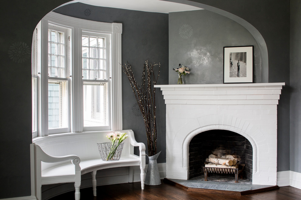 Klassisches Wohnzimmer mit grauer Wandfarbe, dunklem Holzboden, Kaminumrandung aus Backstein und Eckkamin in Boston