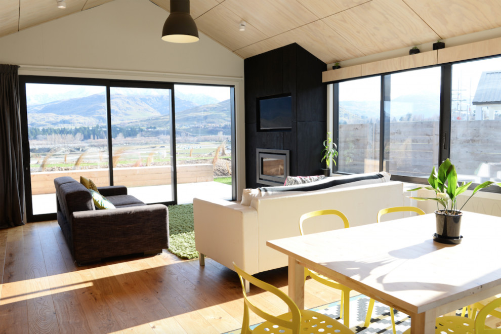 Cette image montre un grand salon design ouvert avec un mur beige, parquet clair, une cheminée standard, un manteau de cheminée en carrelage, un téléviseur fixé au mur et un sol marron.