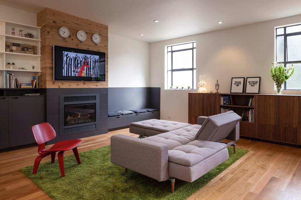サンフランシスコにある中くらいなコンテンポラリースタイルのおしゃれなリビング (白い壁、無垢フローリング、標準型暖炉、金属の暖炉まわり、壁掛け型テレビ、茶色い床) の写真