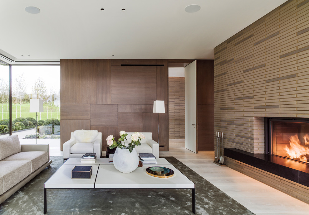 Photo of a contemporary formal open plan living room in London with beige walls, light hardwood flooring, a standard fireplace, a concrete fireplace surround, beige floors and feature lighting.