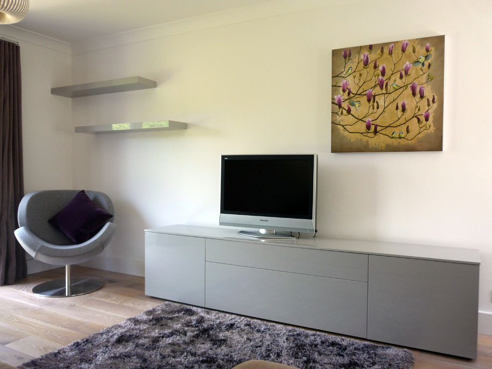 This is an example of a small contemporary enclosed living room in London with white walls, light hardwood flooring, a freestanding tv and no fireplace.