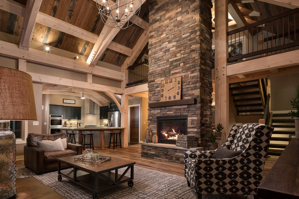 Example of a large mountain style open concept light wood floor living room design in New York with gray walls, a standard fireplace, a stone fireplace and a tv stand