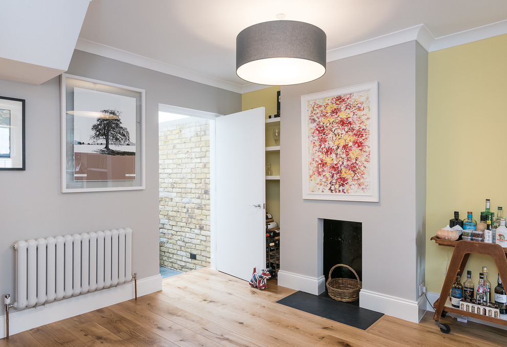ロンドンにある低価格の中くらいなコンテンポラリースタイルのおしゃれなリビング (茶色い壁、淡色無垢フローリング、標準型暖炉、金属の暖炉まわり、据え置き型テレビ、黄色い床) の写真