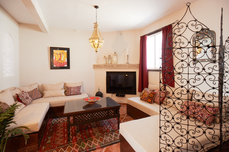 Immagine di un soggiorno tropicale di medie dimensioni e aperto con sala formale, pareti bianche, pavimento in terracotta e parete attrezzata