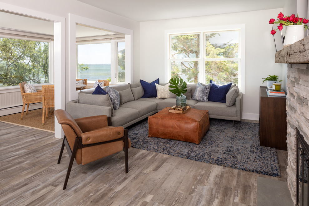 На фото: открытая гостиная комната в морском стиле с серыми стенами, светлым паркетным полом, стандартным камином, фасадом камина из камня и ковром на полу