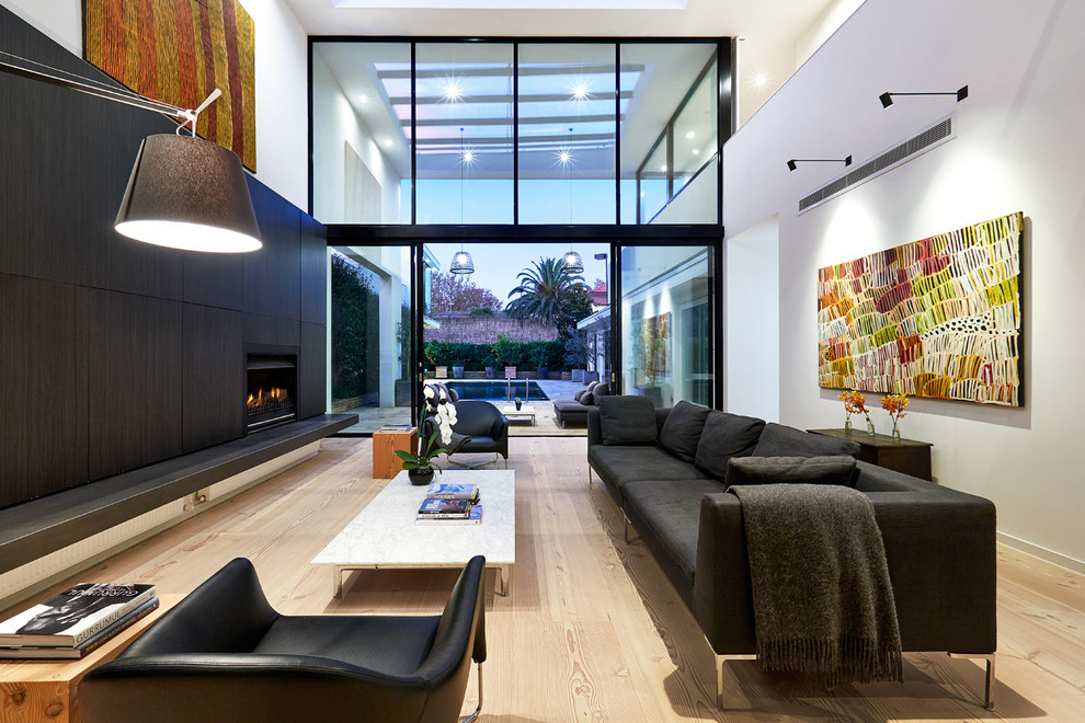 Imagen de salón abierto contemporáneo de tamaño medio sin televisor con paredes blancas, suelo de madera clara y chimenea lineal