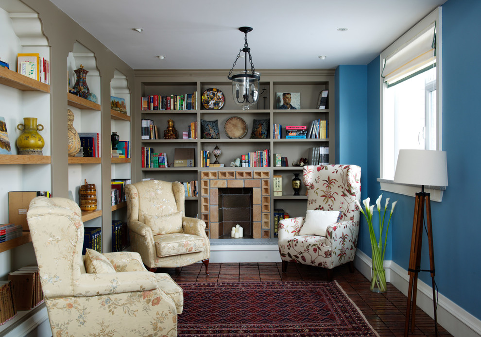 На фото: большая изолированная гостиная комната в стиле фьюжн с с книжными шкафами и полками, синими стенами, кирпичным полом, стандартным камином и фасадом камина из кирпича без телевизора