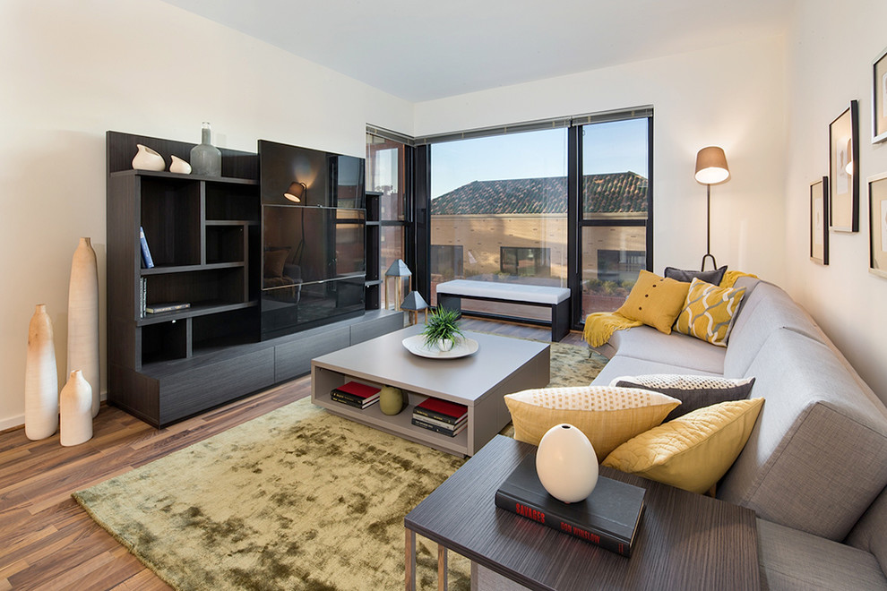 Modernes Wohnzimmer ohne Kamin mit braunem Holzboden und Multimediawand in New York