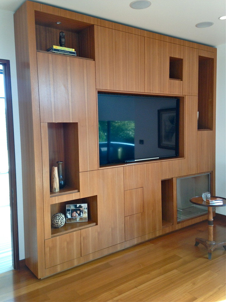 This is an example of a medium sized modern open plan living room in Los Angeles with white walls, light hardwood flooring and a built-in media unit.