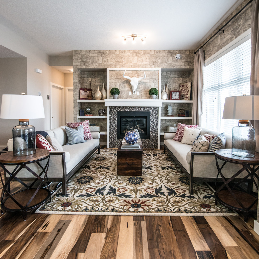 Mittelgroßes, Offenes Rustikales Wohnzimmer mit beiger Wandfarbe, braunem Holzboden, Kamin und gefliester Kaminumrandung in Calgary