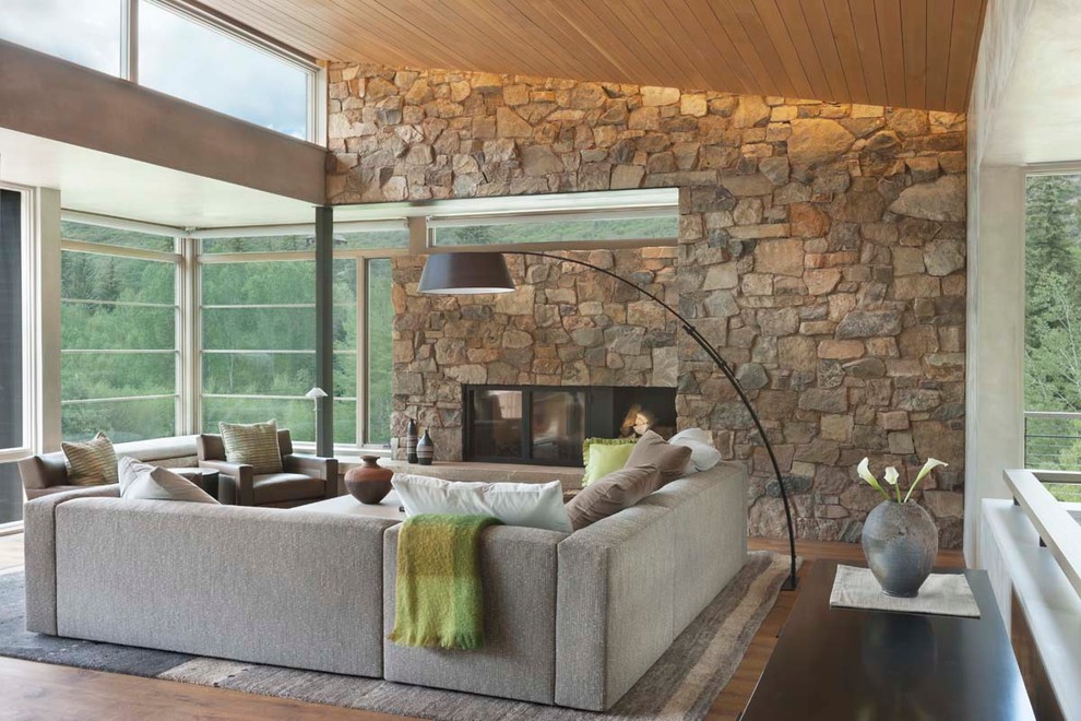 Идея дизайна: большая открытая, парадная гостиная комната в современном стиле с паркетным полом среднего тона, стандартным камином и фасадом камина из камня