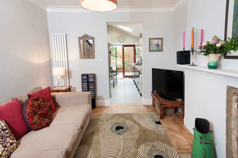 Esempio di un piccolo soggiorno eclettico con parquet chiaro, camino classico, cornice del camino in mattoni e TV autoportante