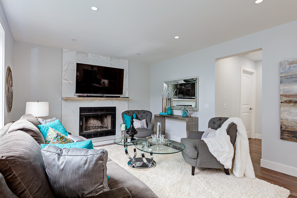 Design ideas for a medium sized traditional grey and teal open plan living room in Calgary with blue walls, medium hardwood flooring, a standard fireplace, a stone fireplace surround and a wall mounted tv.