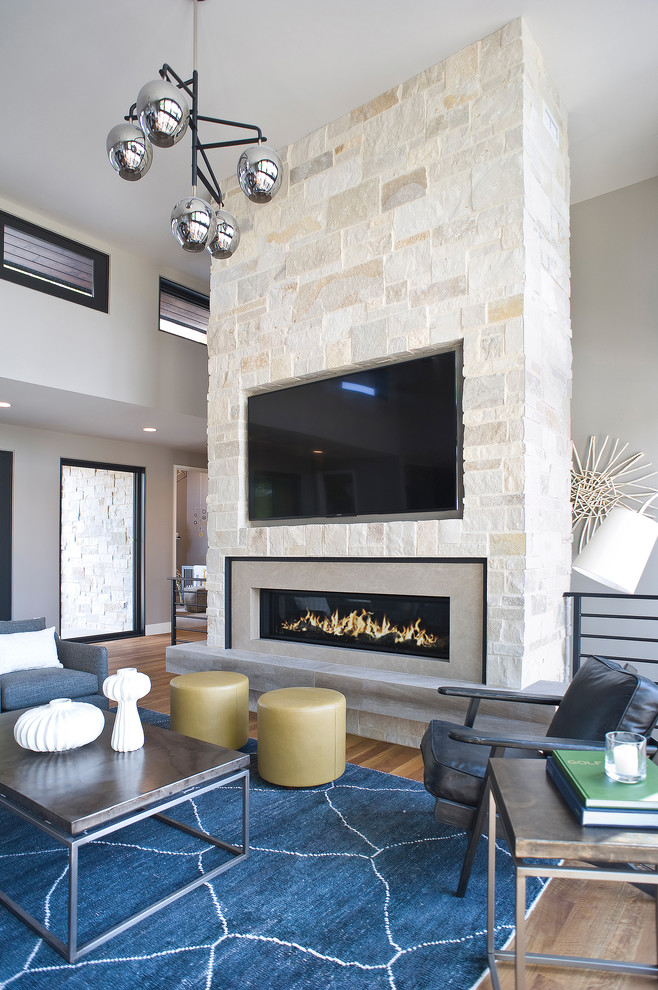 Living room - large modern open concept medium tone wood floor and brown floor living room idea with beige walls, a standard fireplace, a stone fireplace and a wall-mounted tv