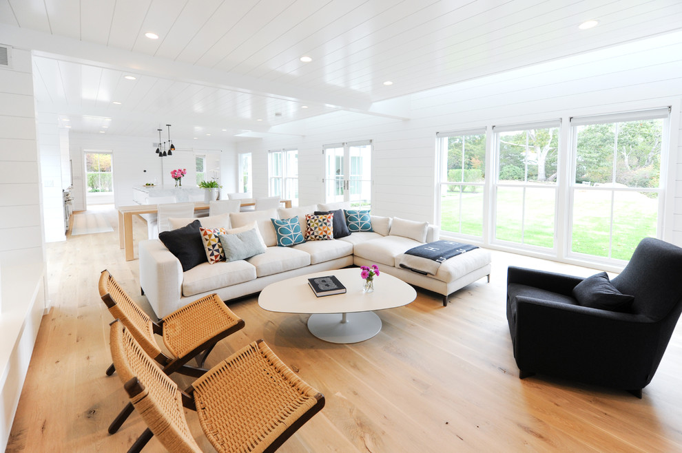 Cette image montre un salon design ouvert avec un mur blanc, un sol en bois brun et aucune cheminée.