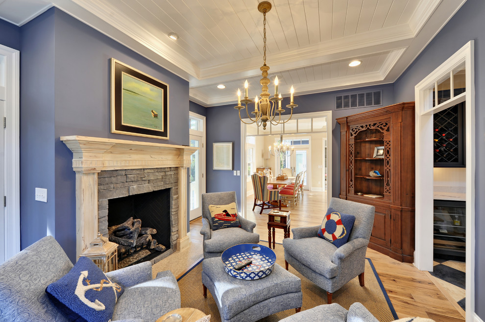 На фото: изолированная гостиная комната в морском стиле с синими стенами, стандартным камином и фасадом камина из камня без телевизора